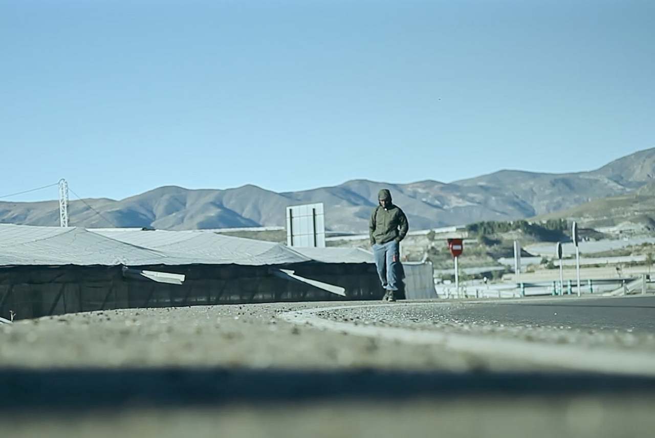 View of worker and greenhouses with hills in background