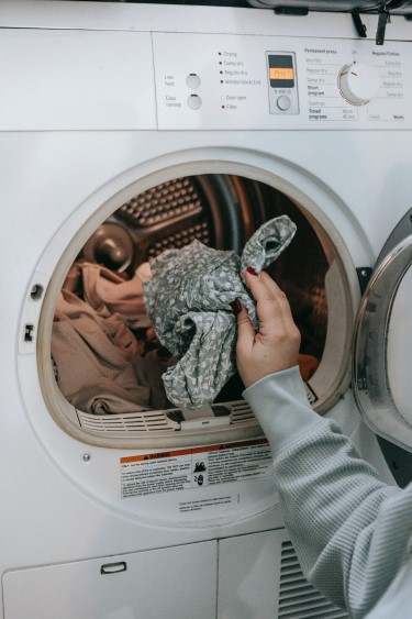 Person putting clothes into a washing machine
